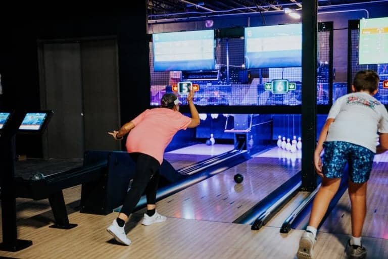 Person bowling, action shot, in a modern alley at Pickle-Pins