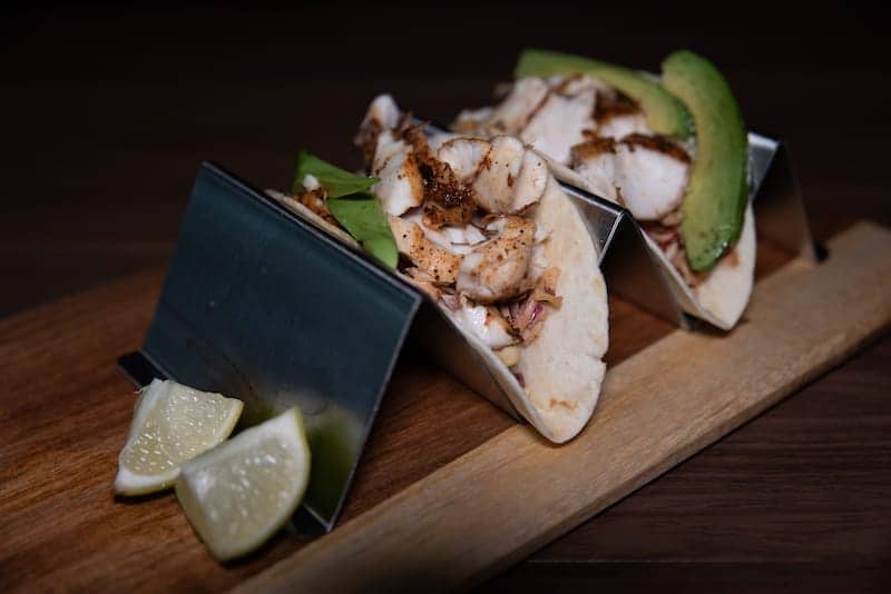 Fish tacos with avocado and lime wedges - Picklenpins in NOLA