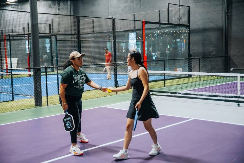 Two women playing pickleball on an indoor court at Pickle-Pins