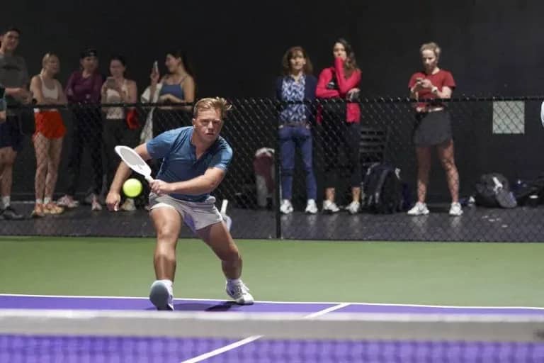 Man on indoor pickleball court swinging paddle - Pickle-Pins