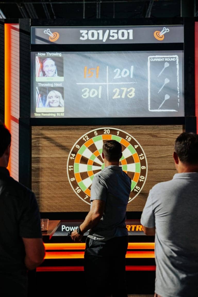 People playing digital darts on a large interactive screen - Pickle-Pins