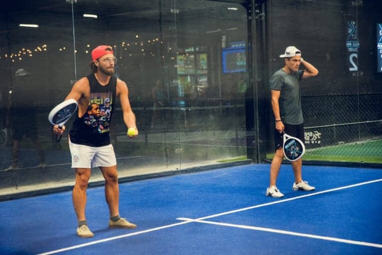 Two men playing pickleball on a blue court at Pickle-Pins