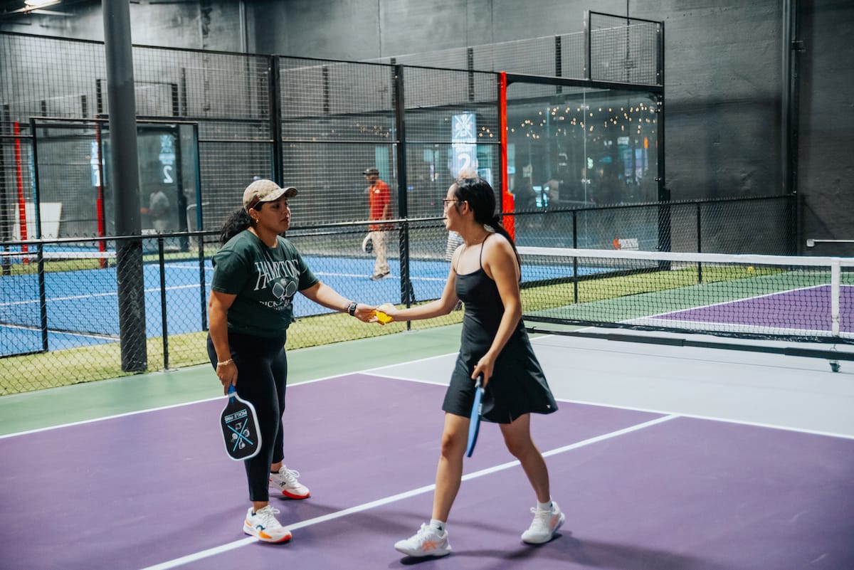 Two women playing pickleball on an indoor court at Pickle-Pins Two women playing pickleball on an indoor court at Pickle-Pins