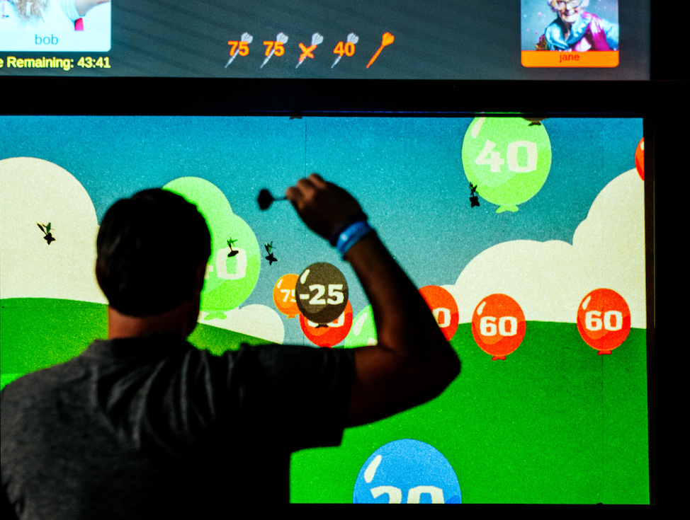 Person playing interactive digital darts at Pickle-Pins