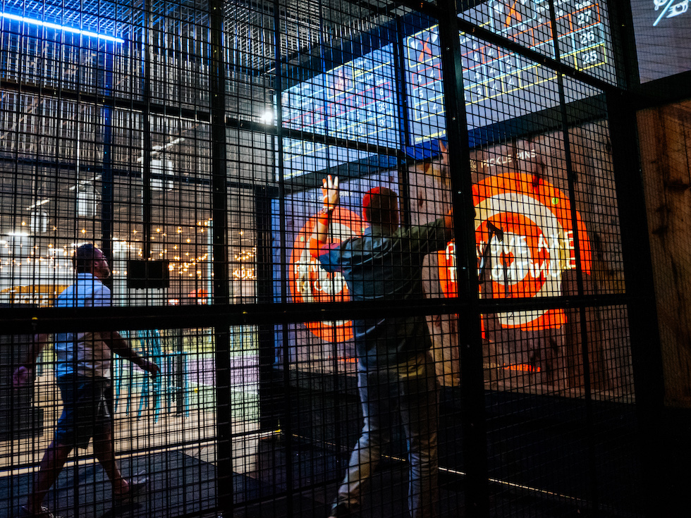 People axe throwing in a caged lane at Pickle-Pins